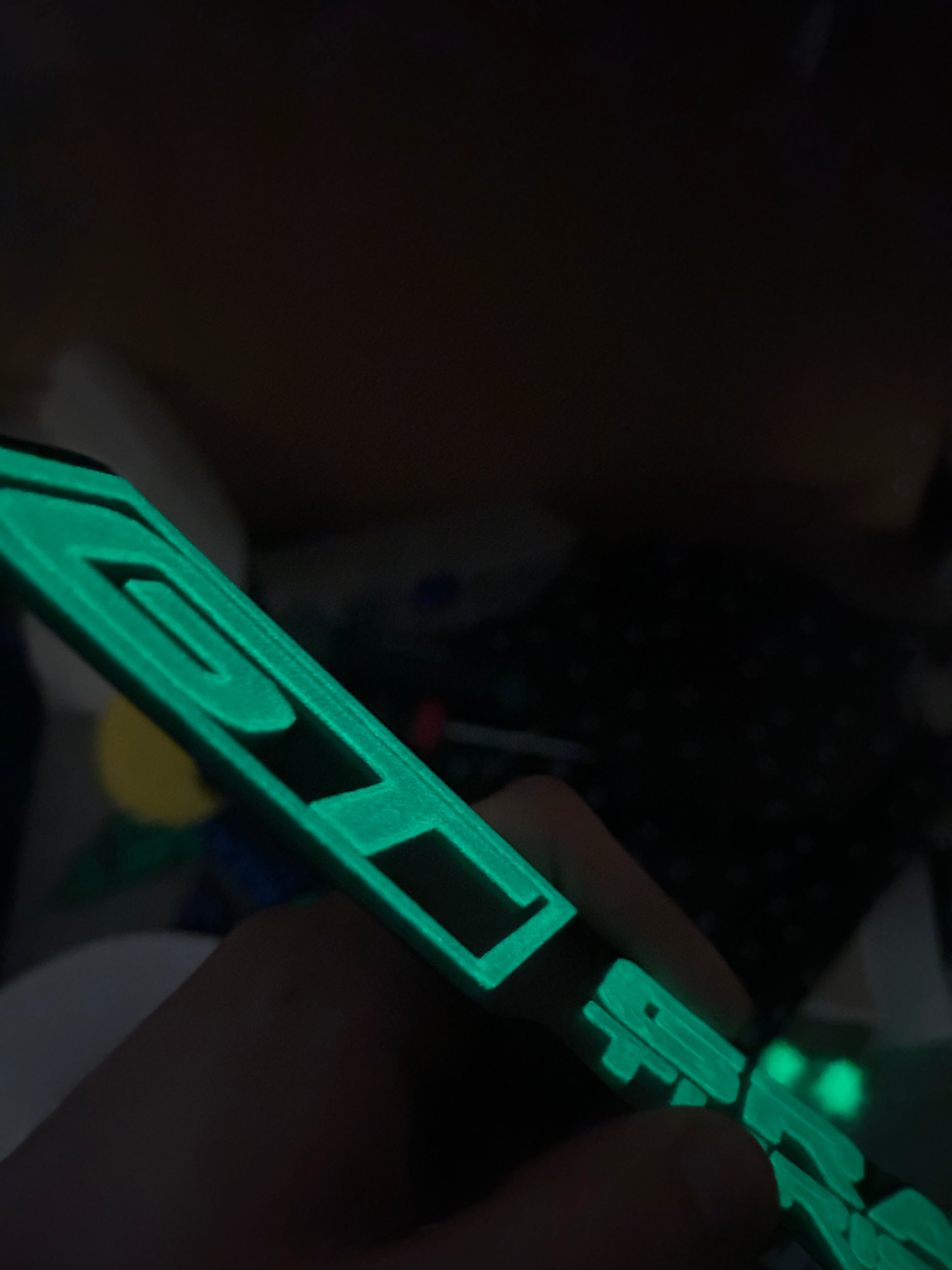 Close-up view of a glowing Gran Turismo Auto Group logo in vibrant green, highlighting the intricate 3D-printed design.