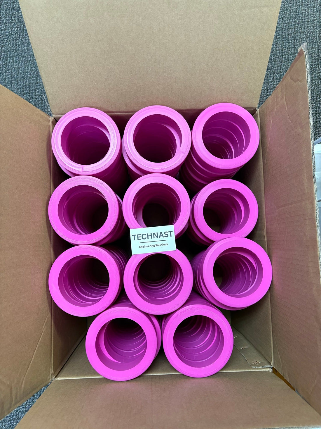 Pink 3D printed display rings stacked in a carton with a TECHNAST card